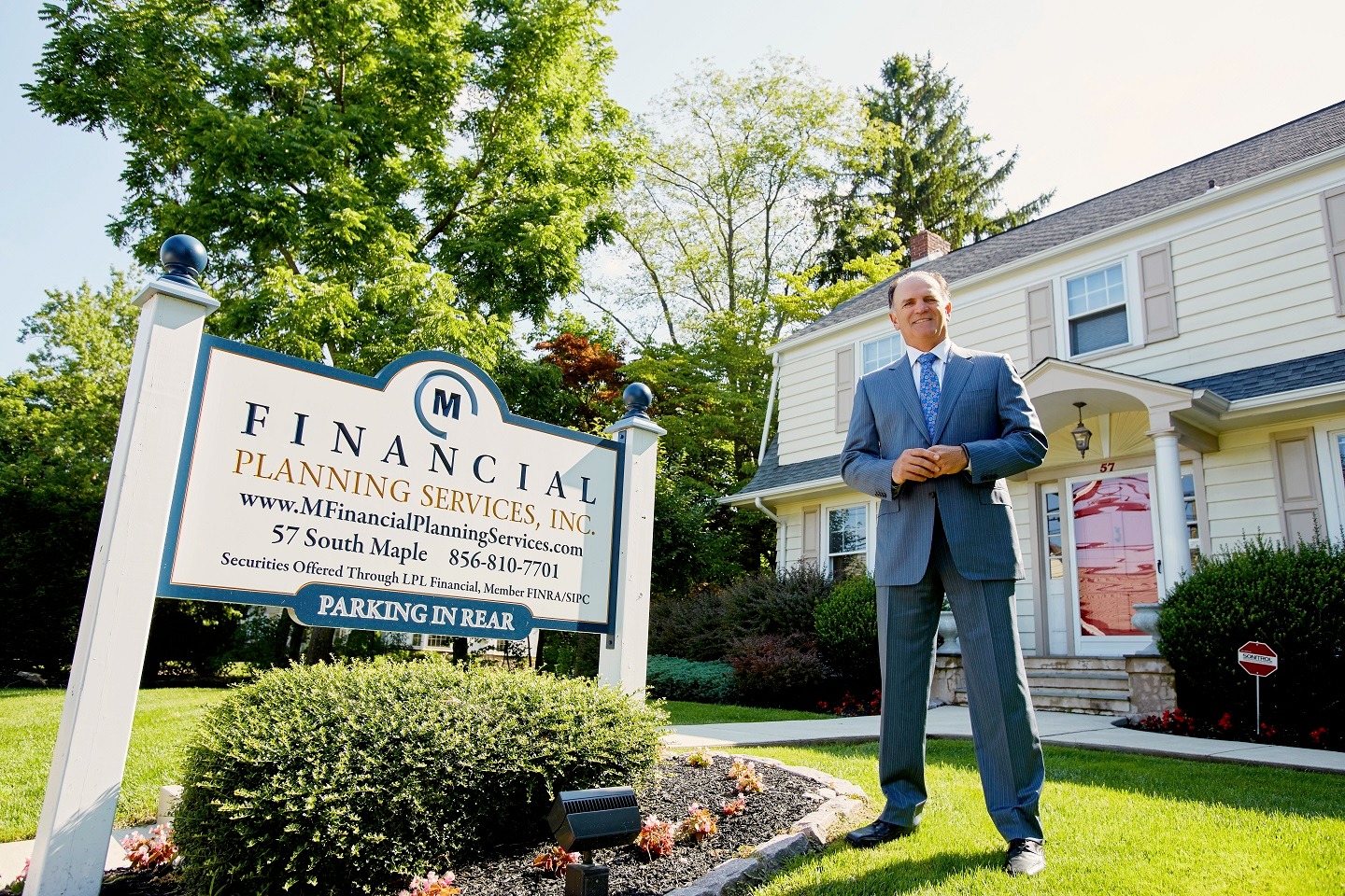 Founder Ted Massaro standing beside the firm sign